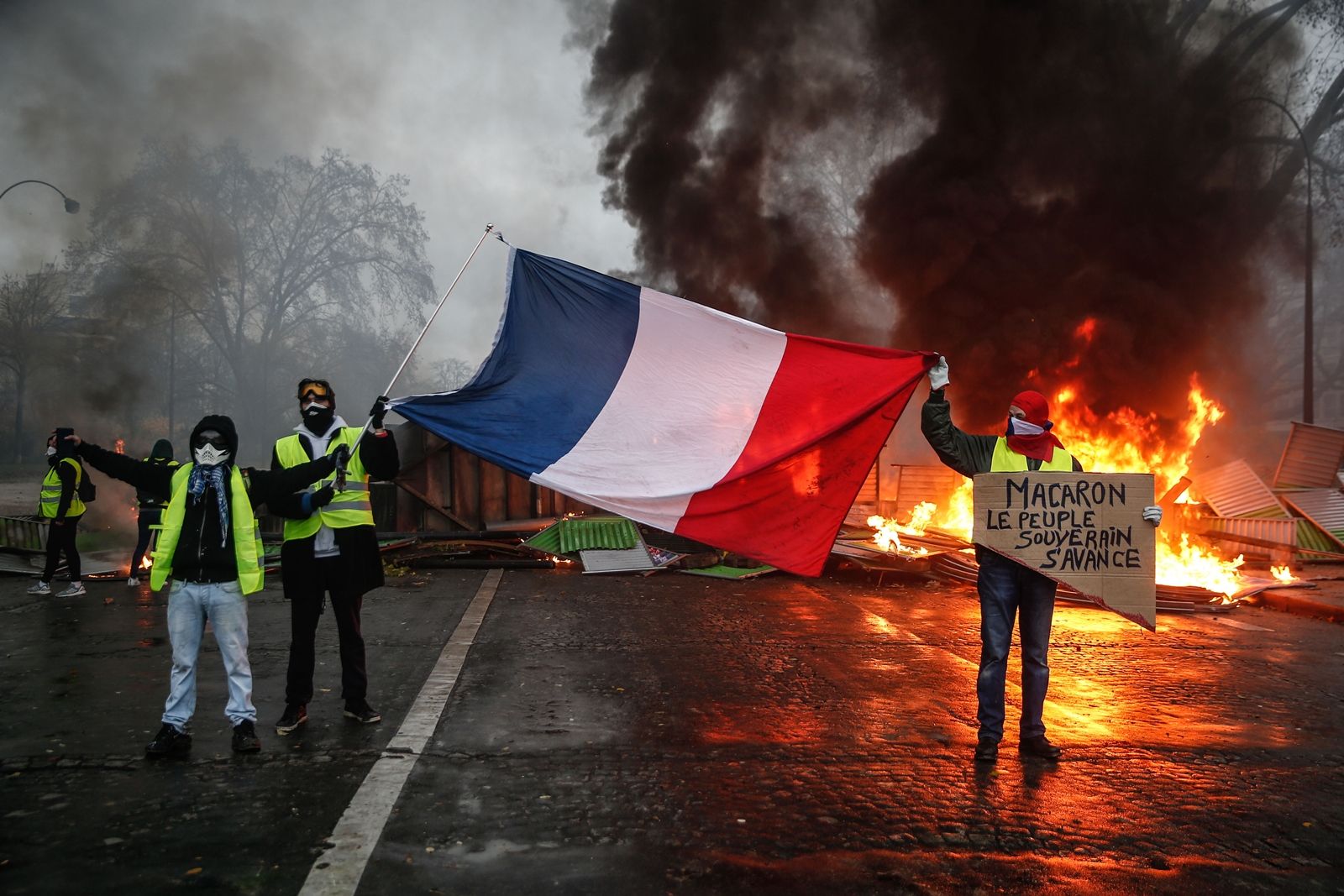 AFP-กลุ่มเสื้อกั๊กเหลืองประท้วงการขึ้นภาษีน้ำมันของรัฐบาลฝรั่งเศส-ถือป้ายด่ามาครง.jpg